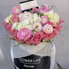 Pink and white flowers in a box with ranunculuses and roses