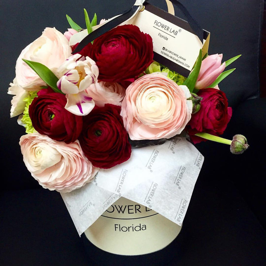Ranunculuses and tulips in a hat box